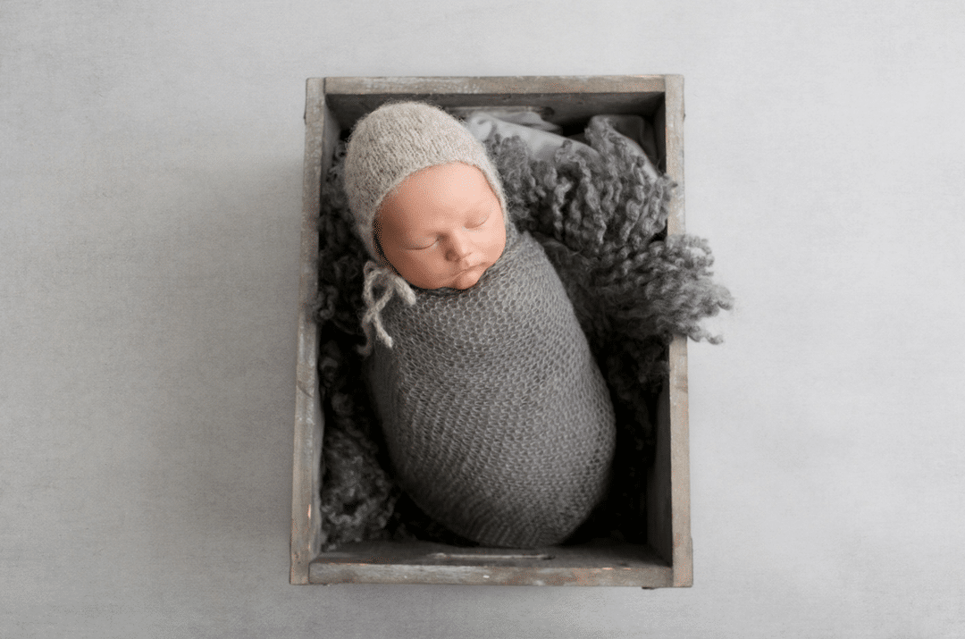 A newborn baby is sleeping in a wooden box.