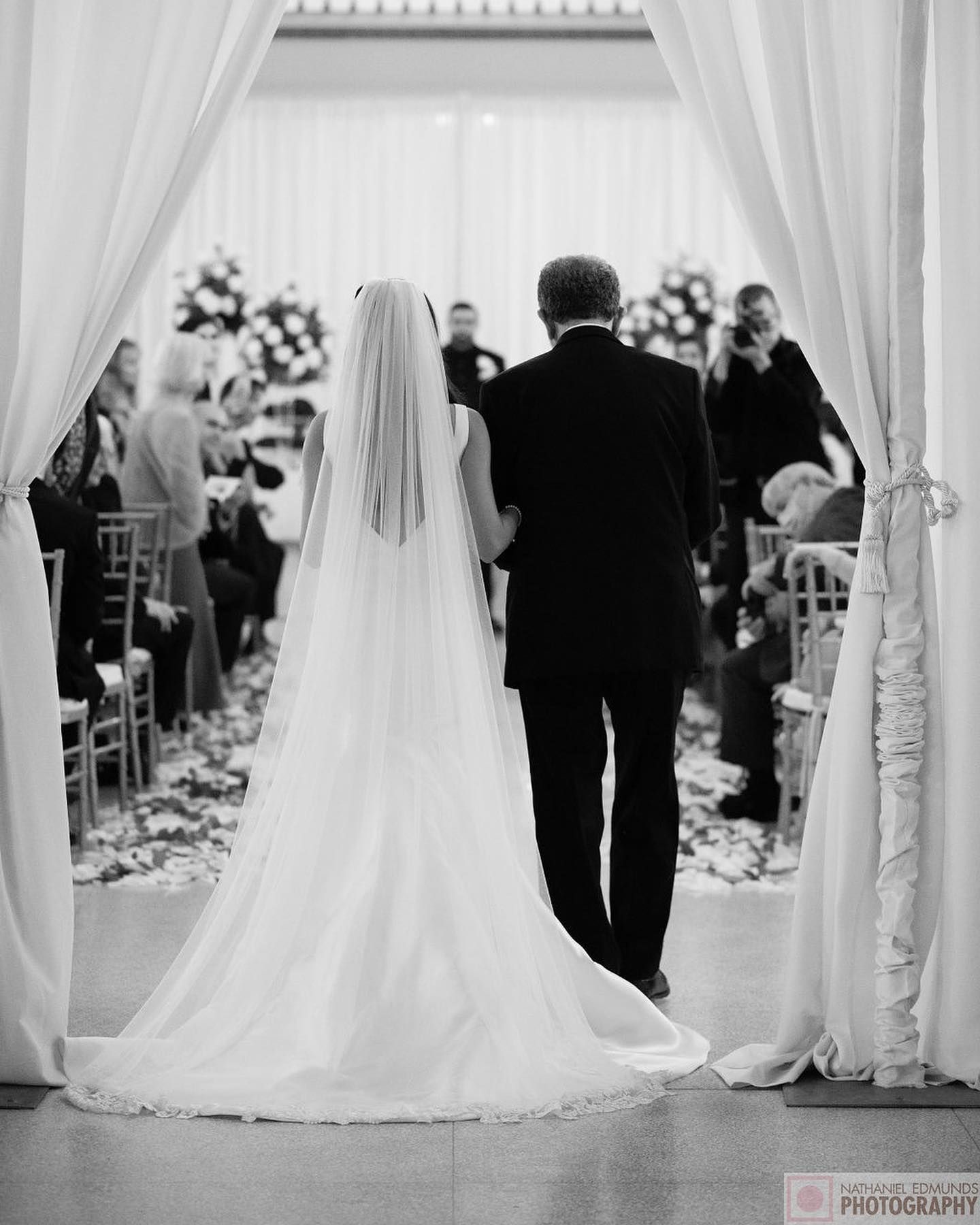 A black and white photo of a bride and groom walking down the aisle