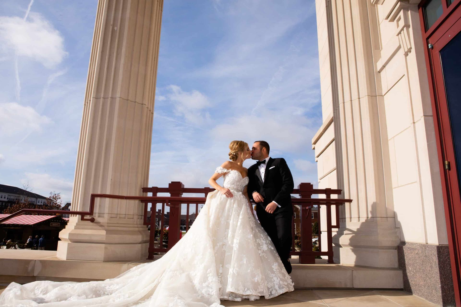 A bride and groom are kissing in front of a building.