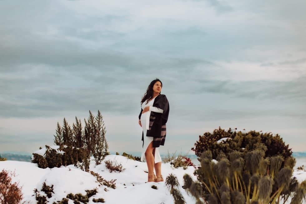 A woman is standing on top of a snow covered hill.