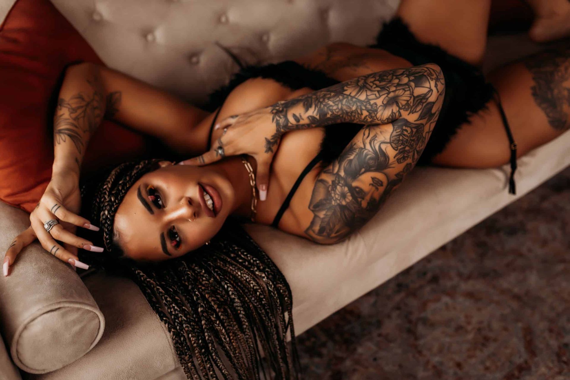 Boudoir photoshoot of a girl with braids and tattoos on a sofa