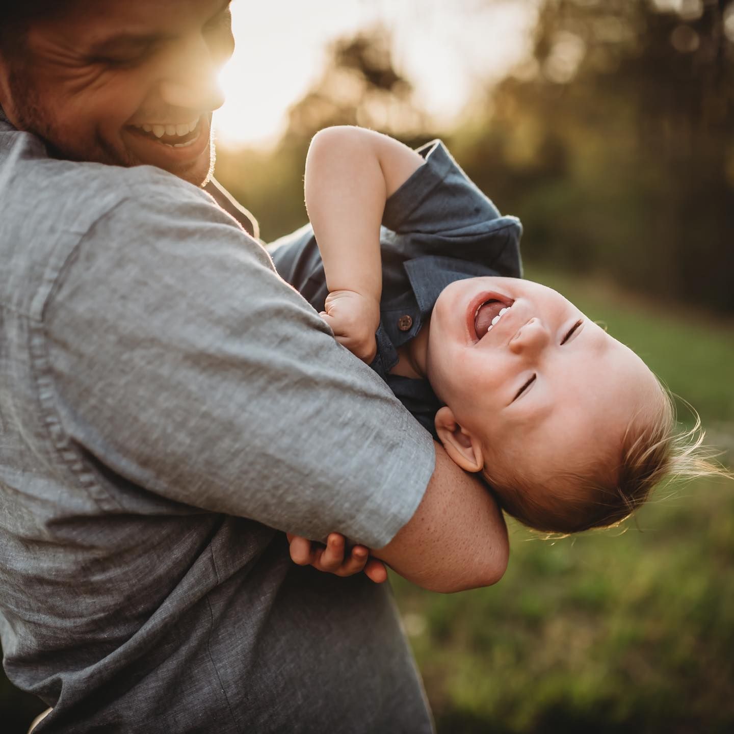 A man is holding a baby in his arms and the baby is laughing.
