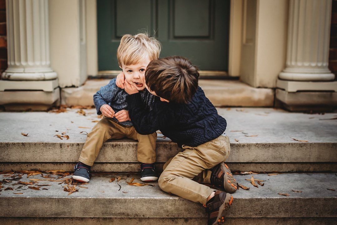 Two young boys are sitting on the steps of a building.