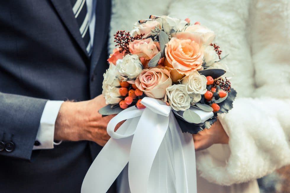 A bride and groom are holding a bouquet of flowers.
