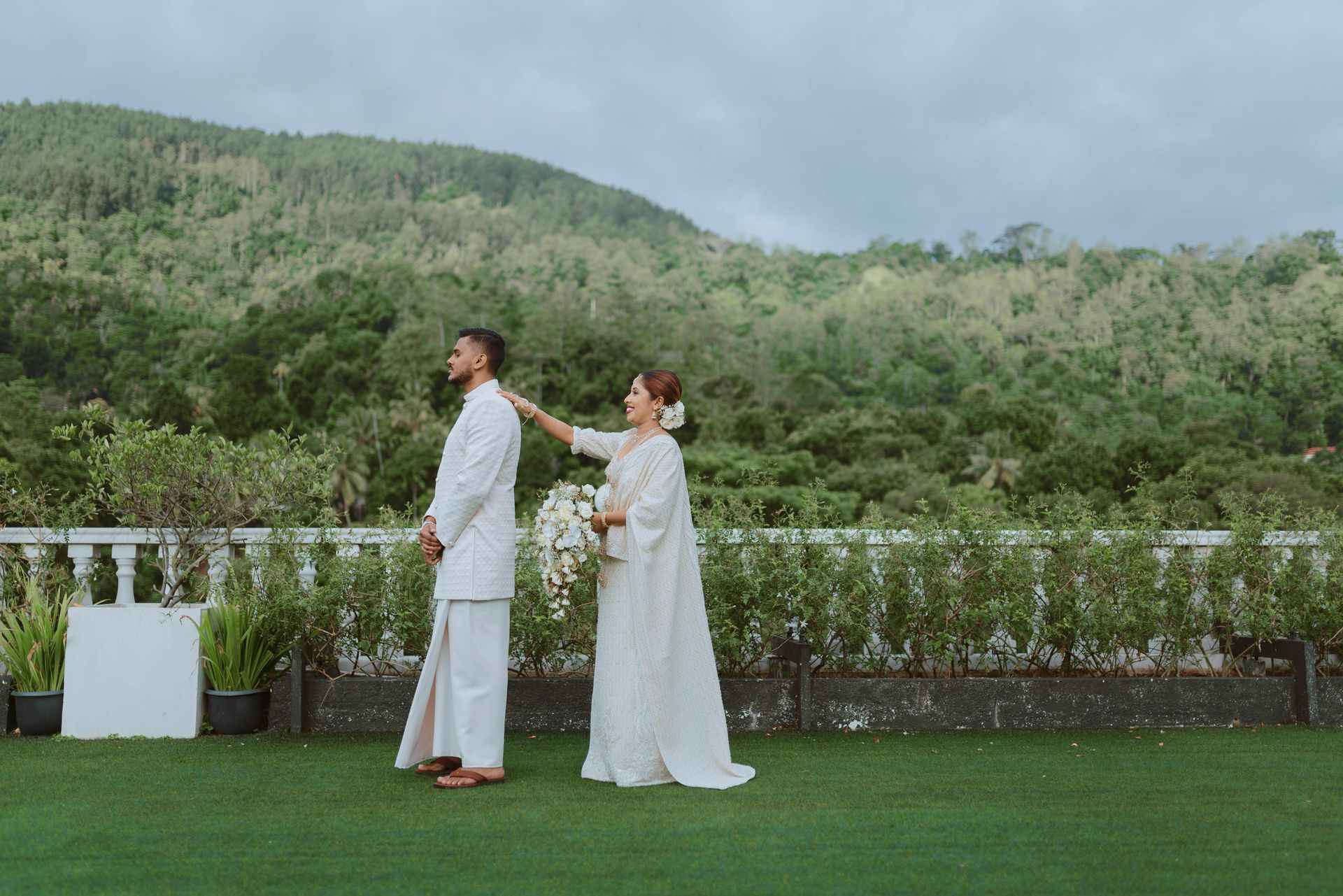 A bride and groom are standing next to each other on a lush green field.