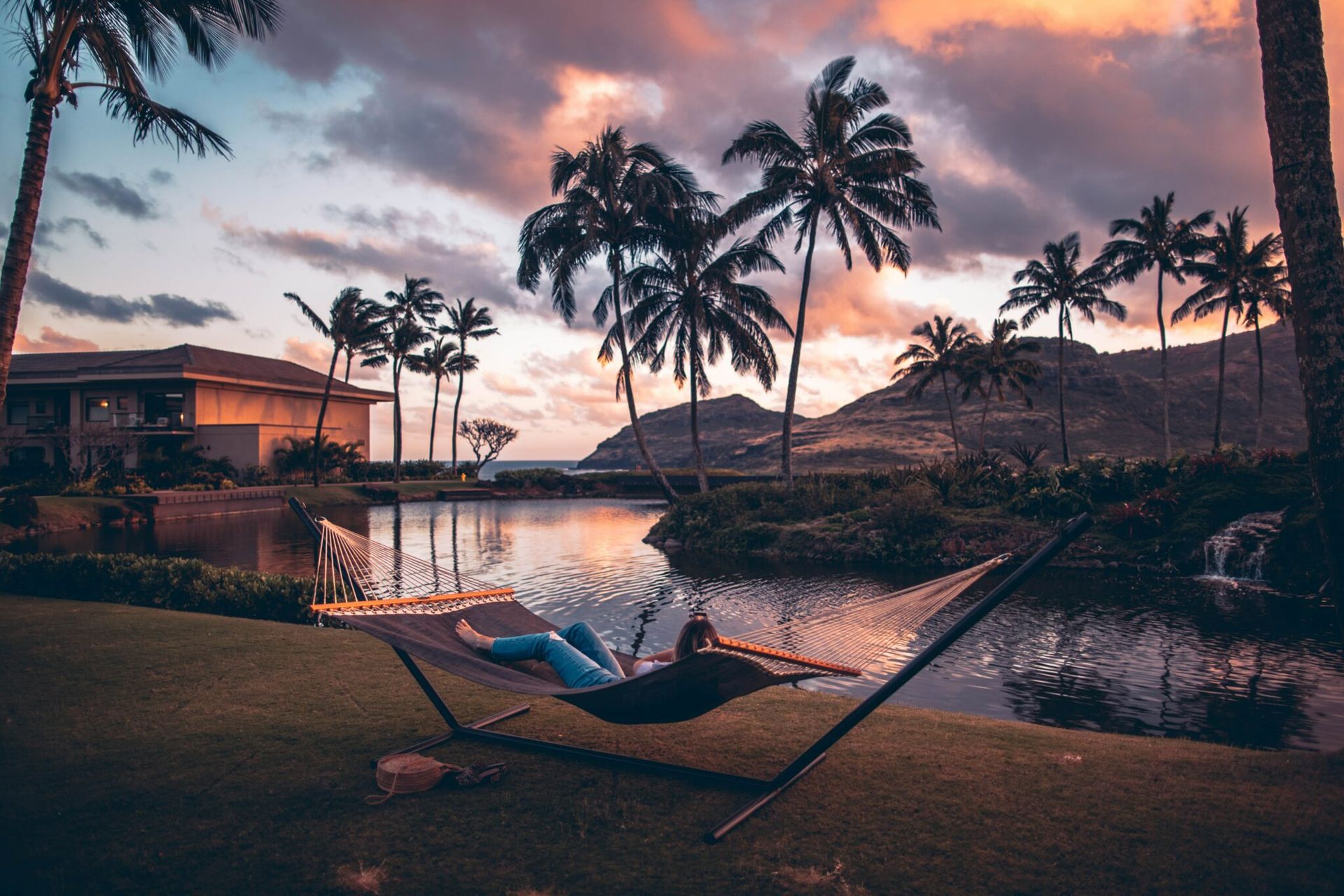 A person is laying in a hammock next to a body of water.