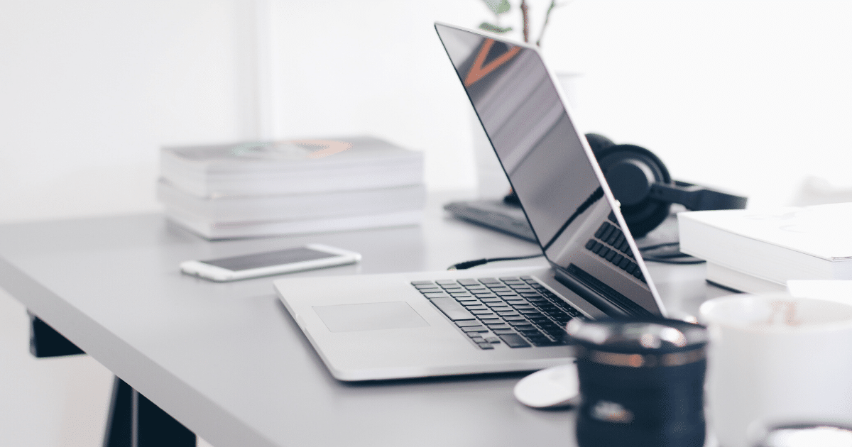 A laptop computer is open on a desk next to a cup of coffee.