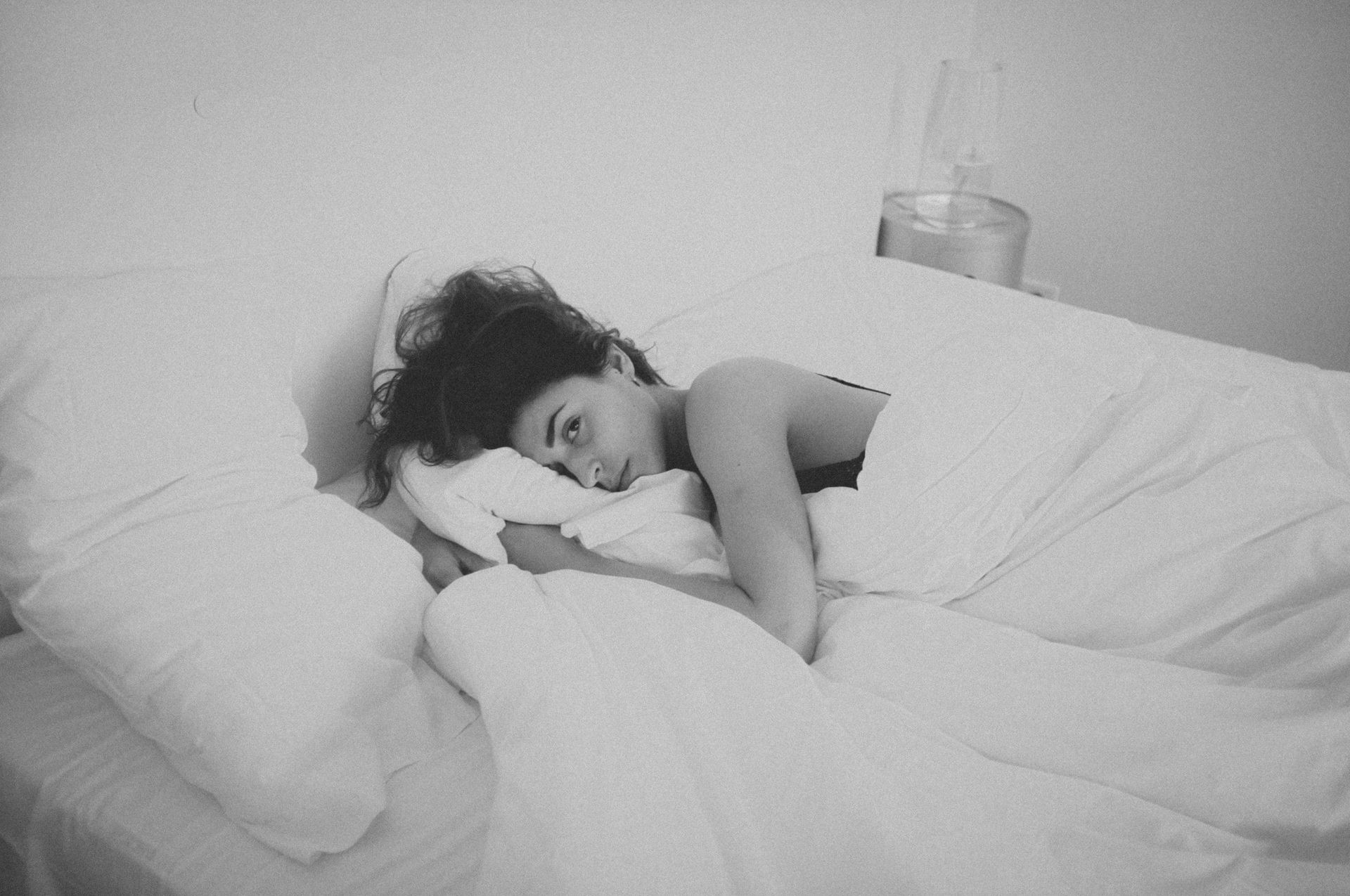 A woman is laying in bed with her head on a pillow.