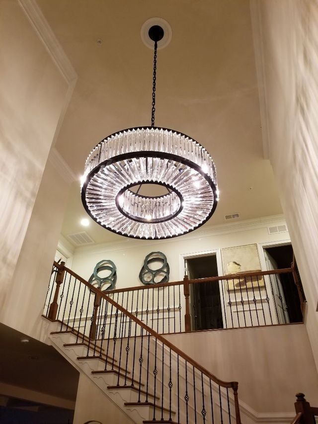 A large chandelier hangs from the ceiling above a staircase
