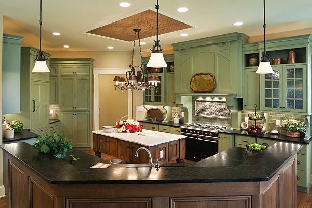 A kitchen with green cabinets and black counter tops