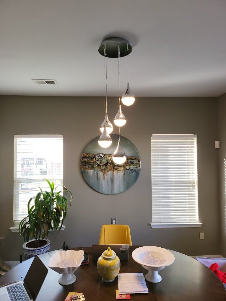 A dining room table with a laptop on it and a painting on the wall above it.