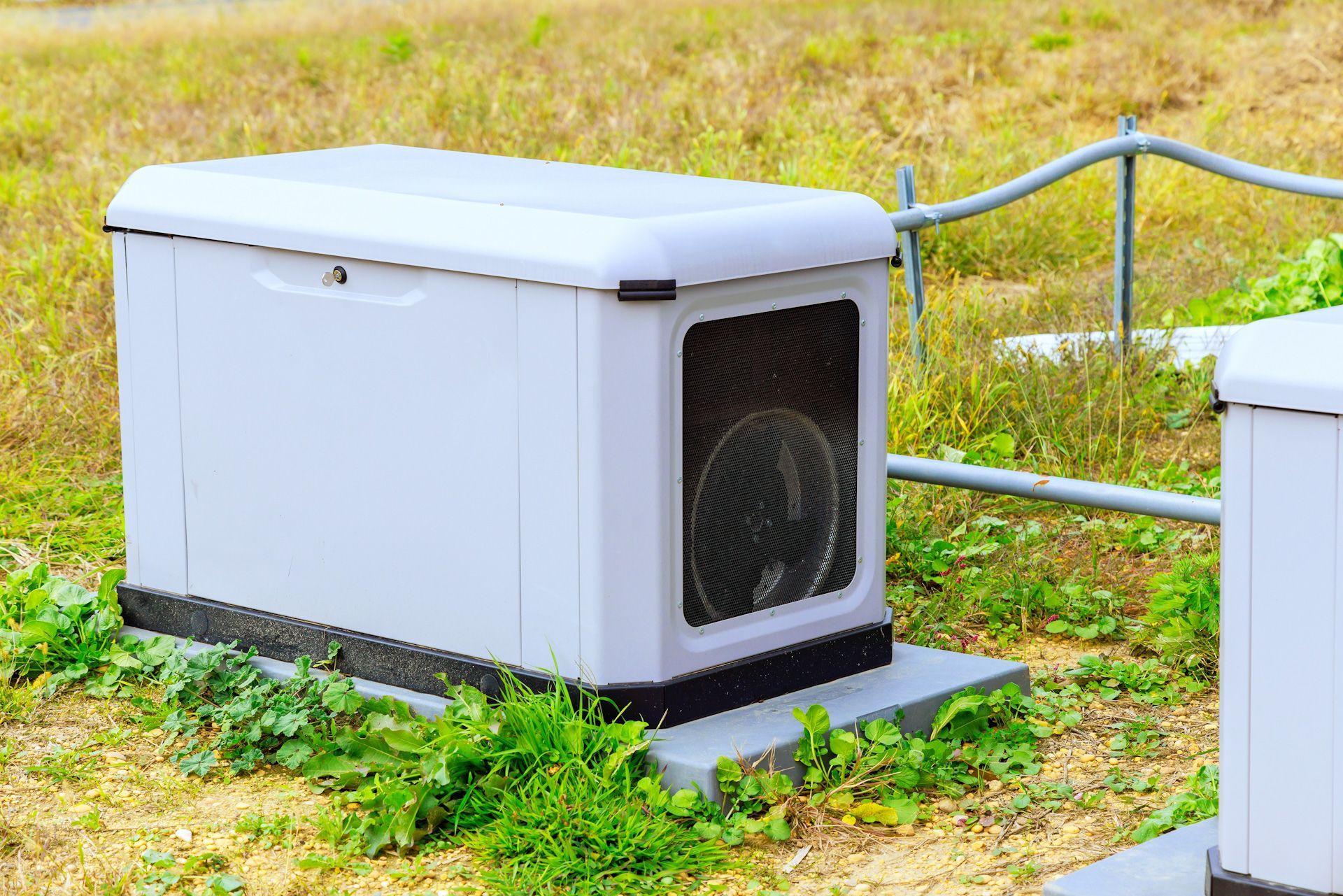A white generator is sitting in the middle of a grassy field.