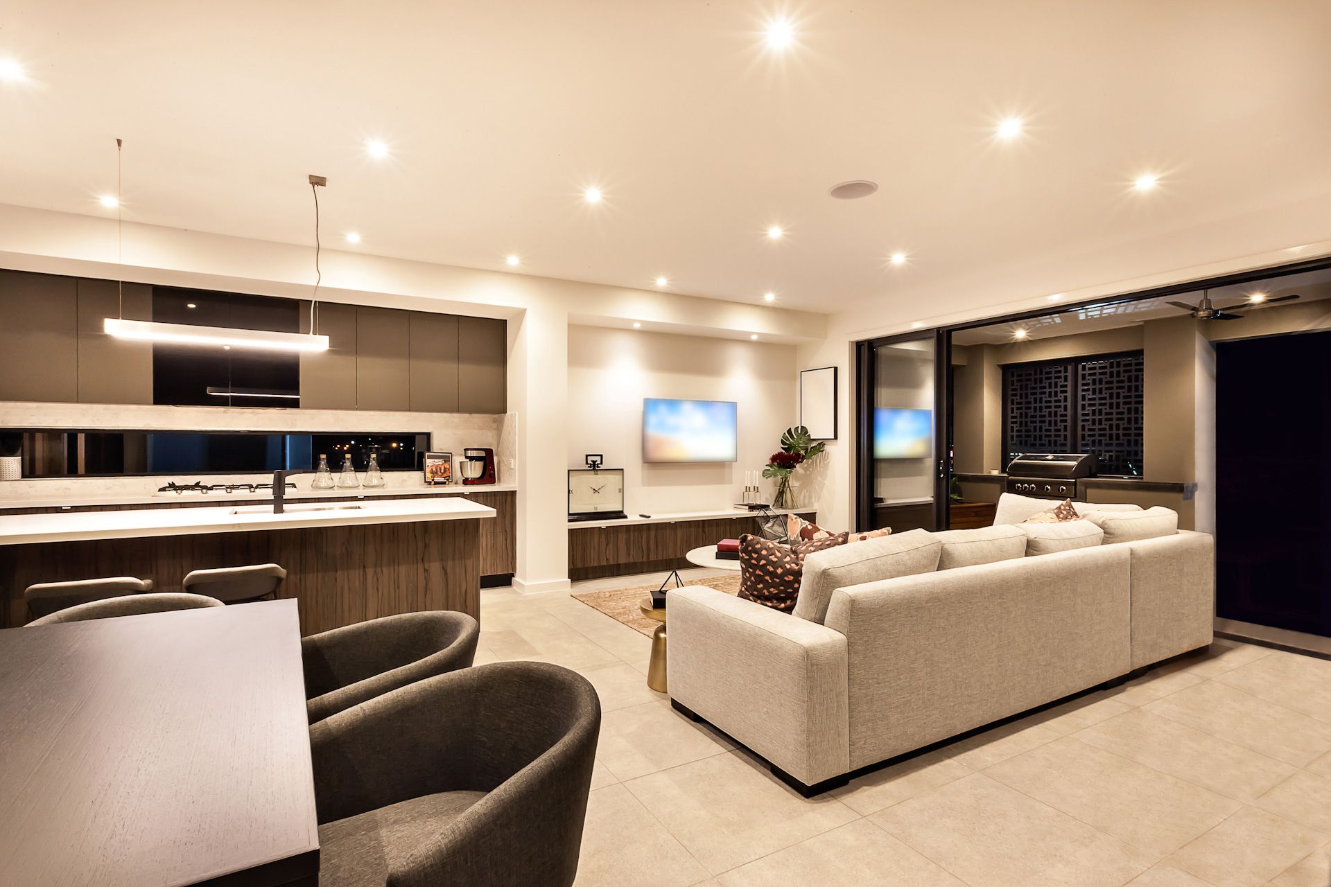 A living room with a couch and chairs and a kitchen