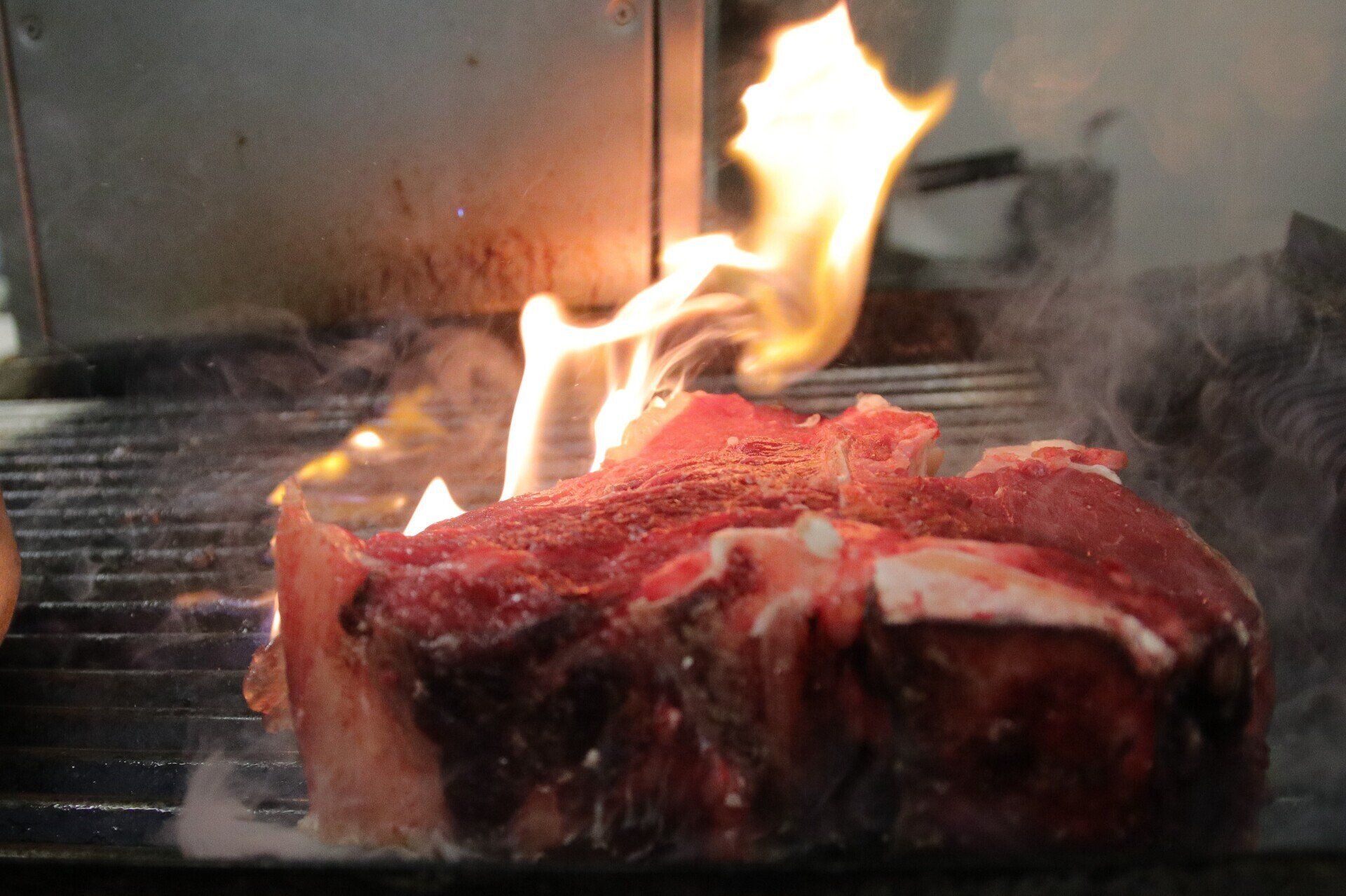 Bistecca alla griglia con fiamme. Carne che cuoce sul fuoco.