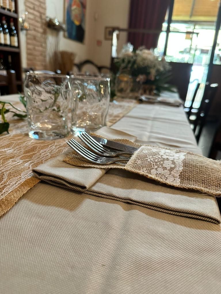 Apparecchiatura della tavola con bicchieri, posate e tovaglioli; colori neutri, allestimento da ristorante.