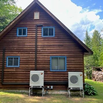 A wooden house with two air conditioners on the side of it.