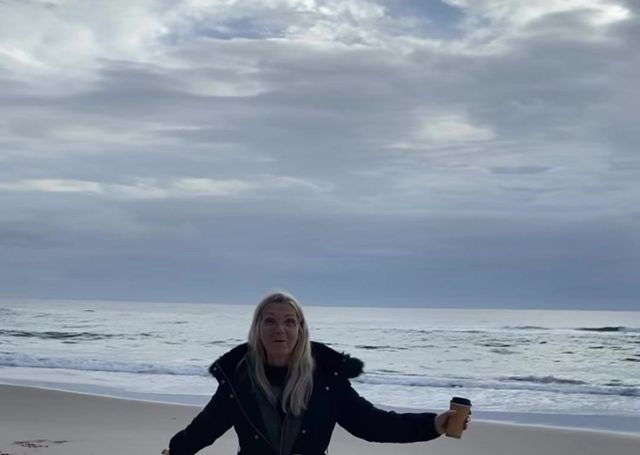 Sandie on the beach with her arms open