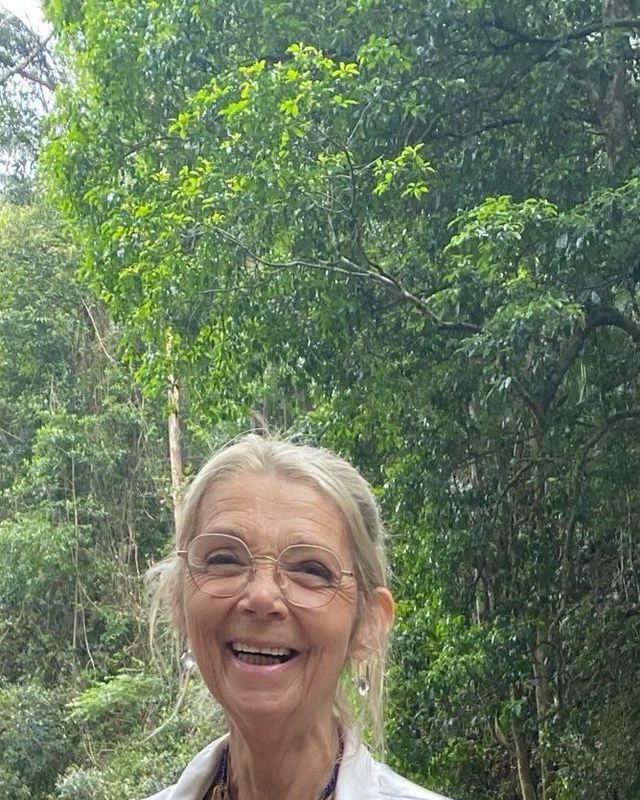 Sandie smiling among tall rainforest trees