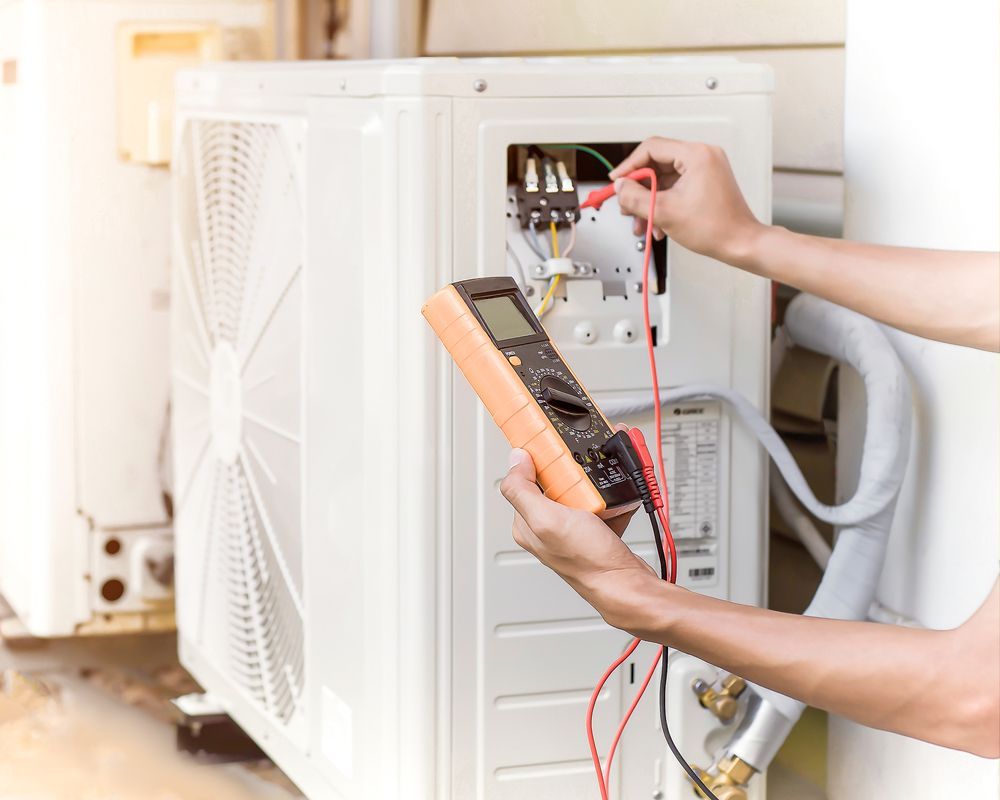 Technician using a multimeter to test an outdoor HVAC unit