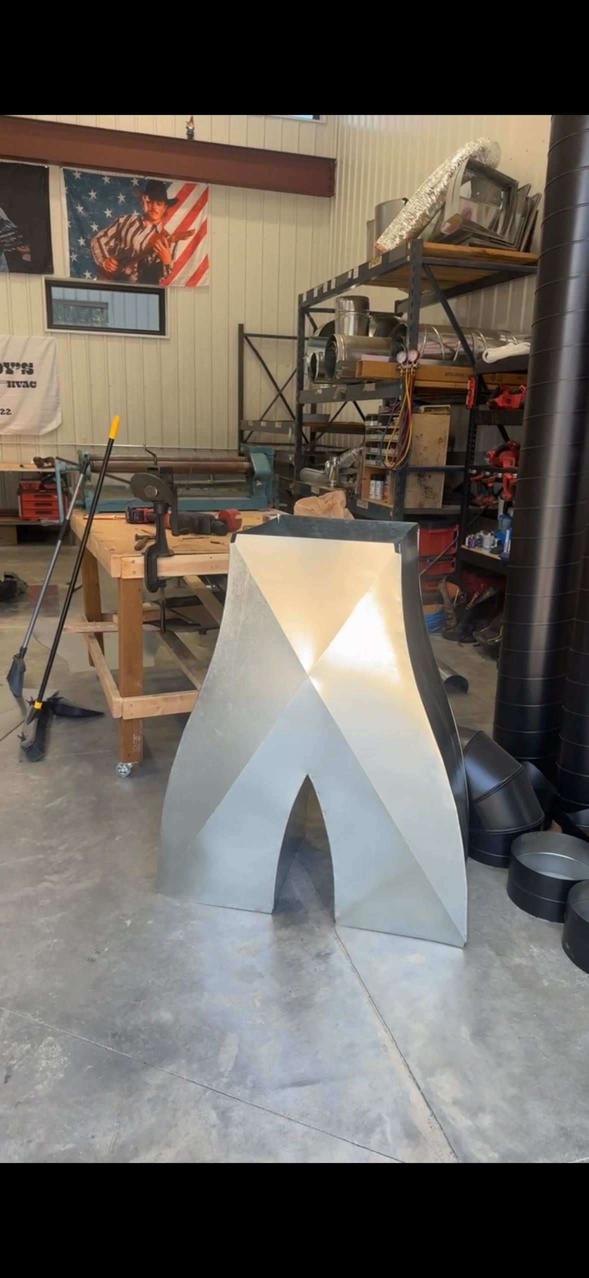 White A-frame sign on a concrete floor in a garage workshop with tools and shelves in the background