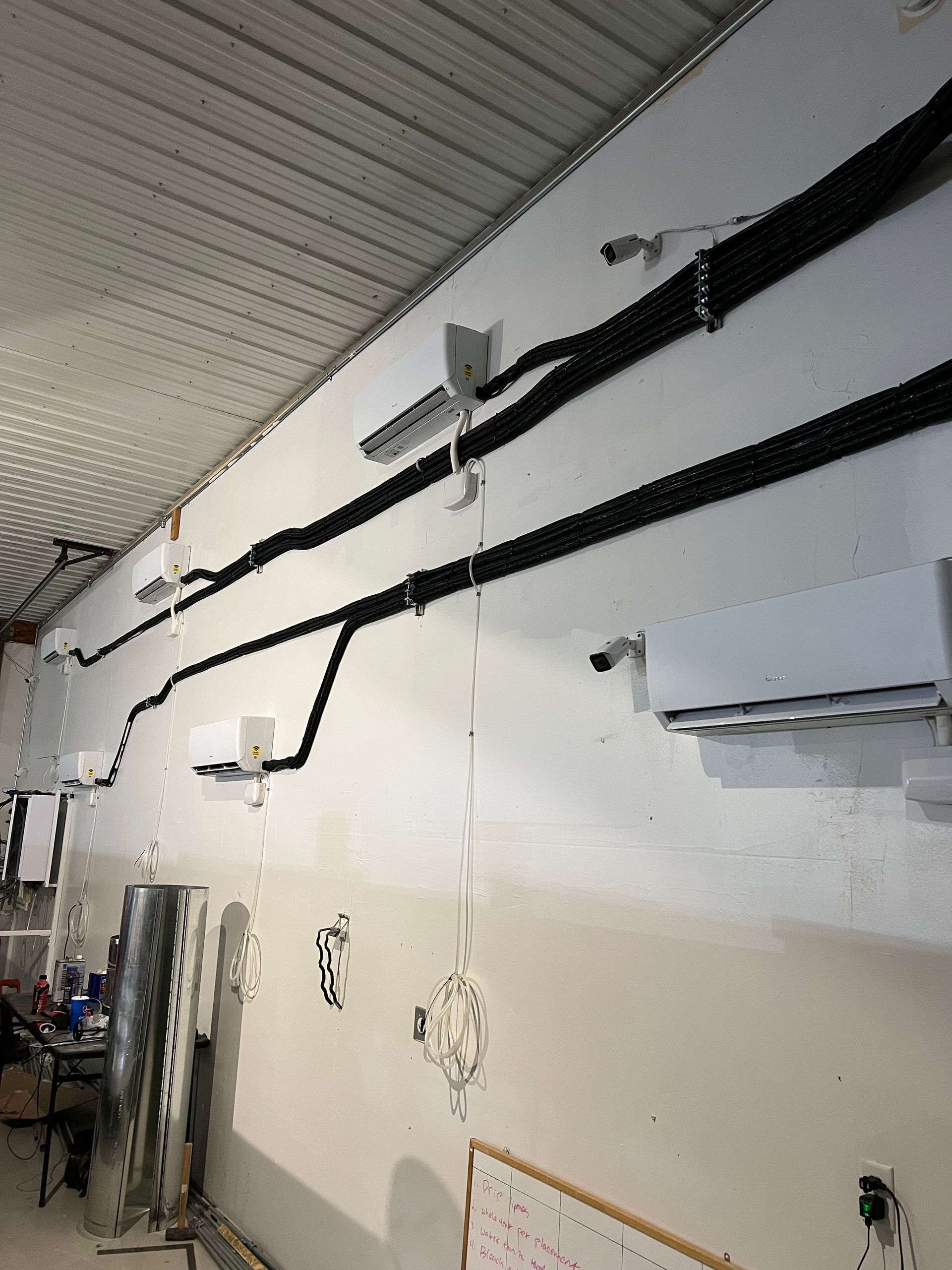 Industrial wall with black cables and conduit mounted along a white interior wall and ceiling