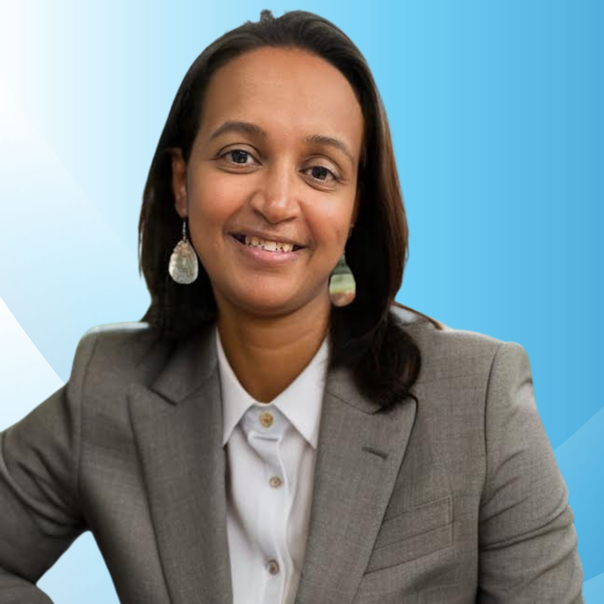 A woman in a suit and earrings smiles for the camera
