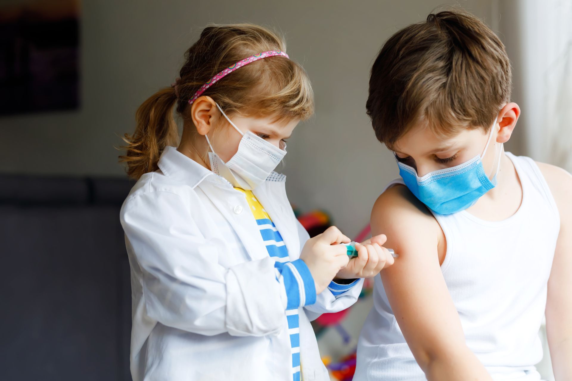 A boy and a girl wearing masks are playing doctors.