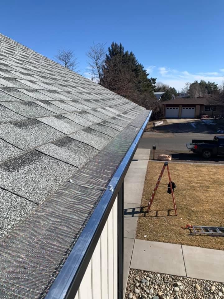 A gutter on the side of a house next to a roof.