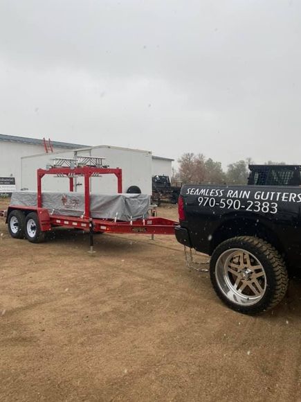A truck with a trailer attached to it is parked in a dirt lot.