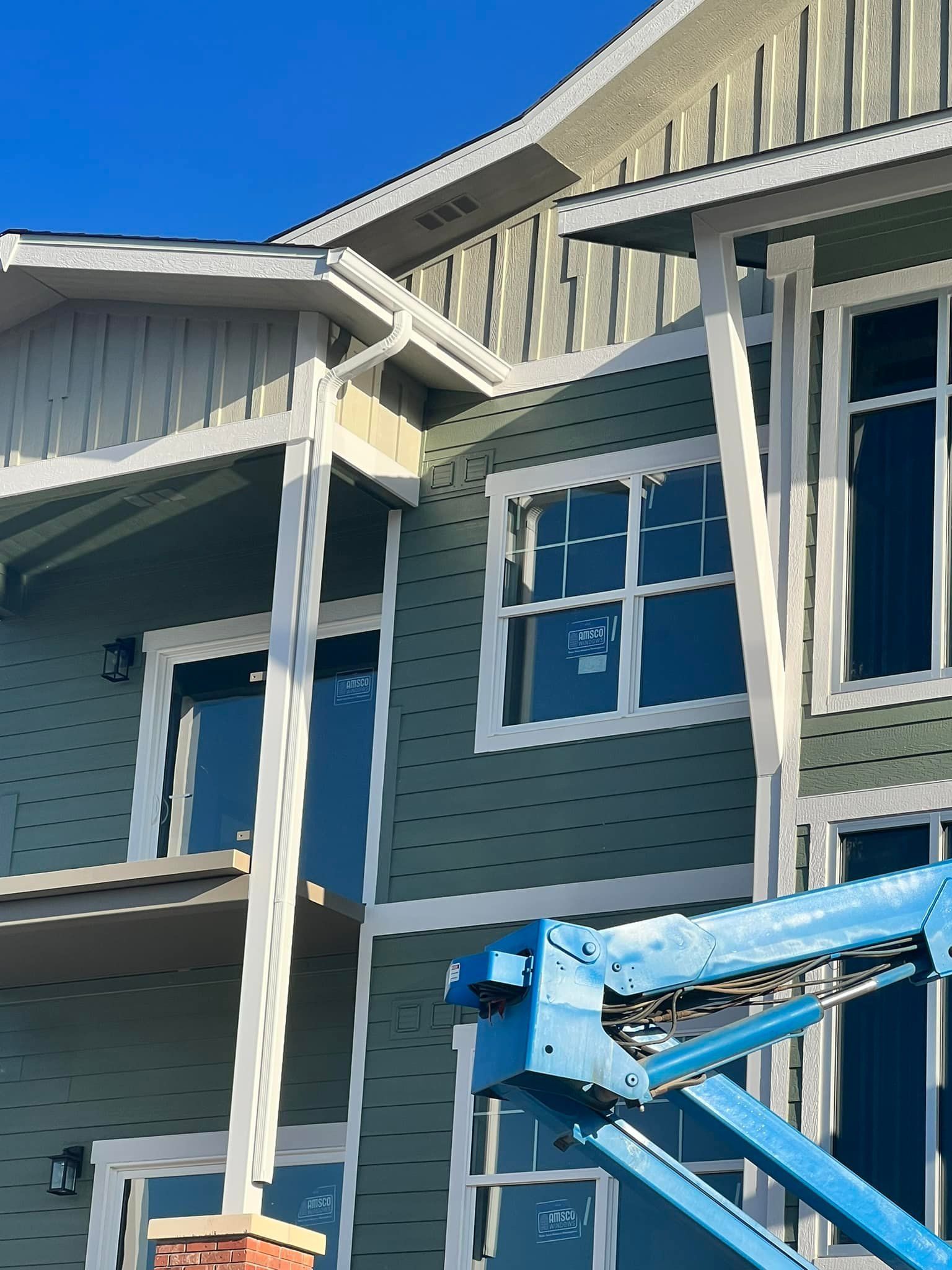 A house is being built with a blue crane in front of it.