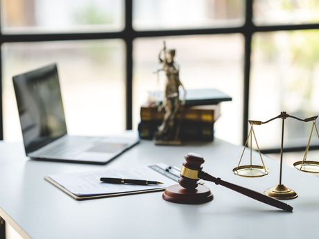 A judge 's gavel , scales of justice , and a laptop on a desk.