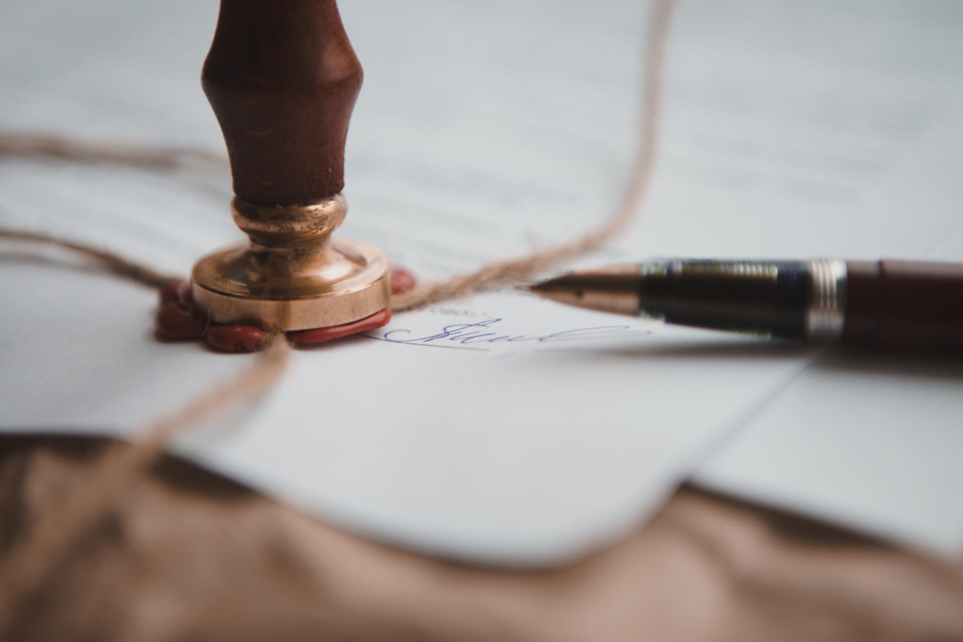 A close up of a wax seal and a pen on a piece of paper.