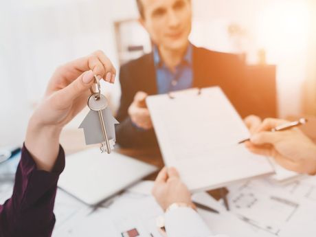 A man is holding a house key in front of a group of people.