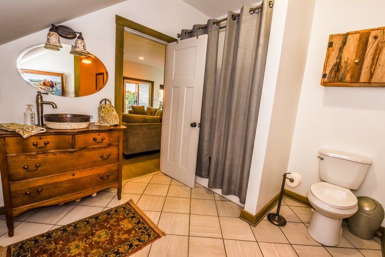 Bathroom with vanity, toilet, shower curtain, and open door to living area.