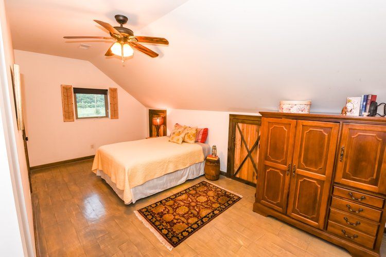 Bedroom with bed, wooden armoire, and small window.