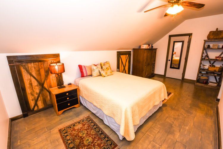 Bedroom with wood floors, bed, nightstand, and shelving.