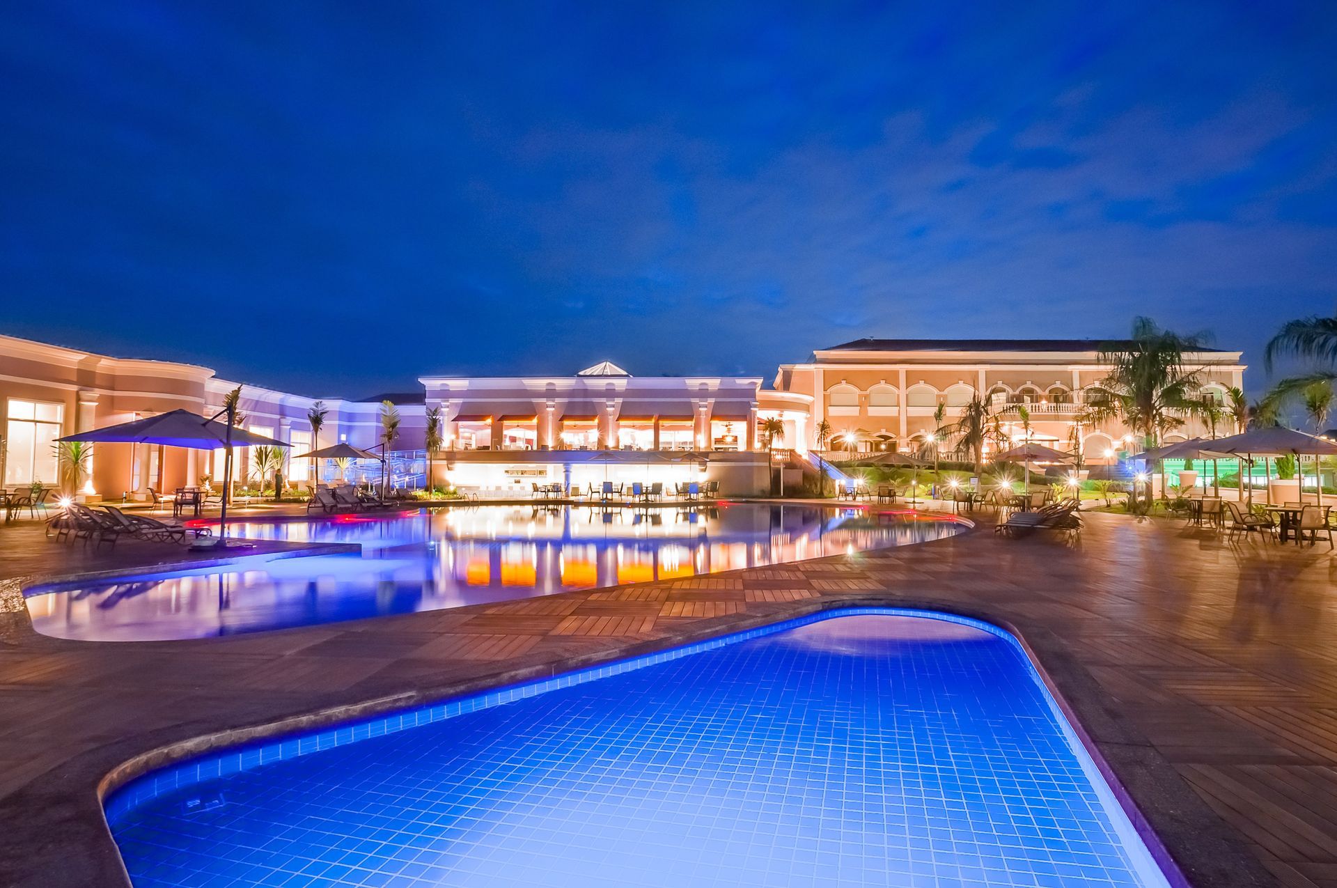 Uma grande piscina em frente a um grande edifício à noite.
