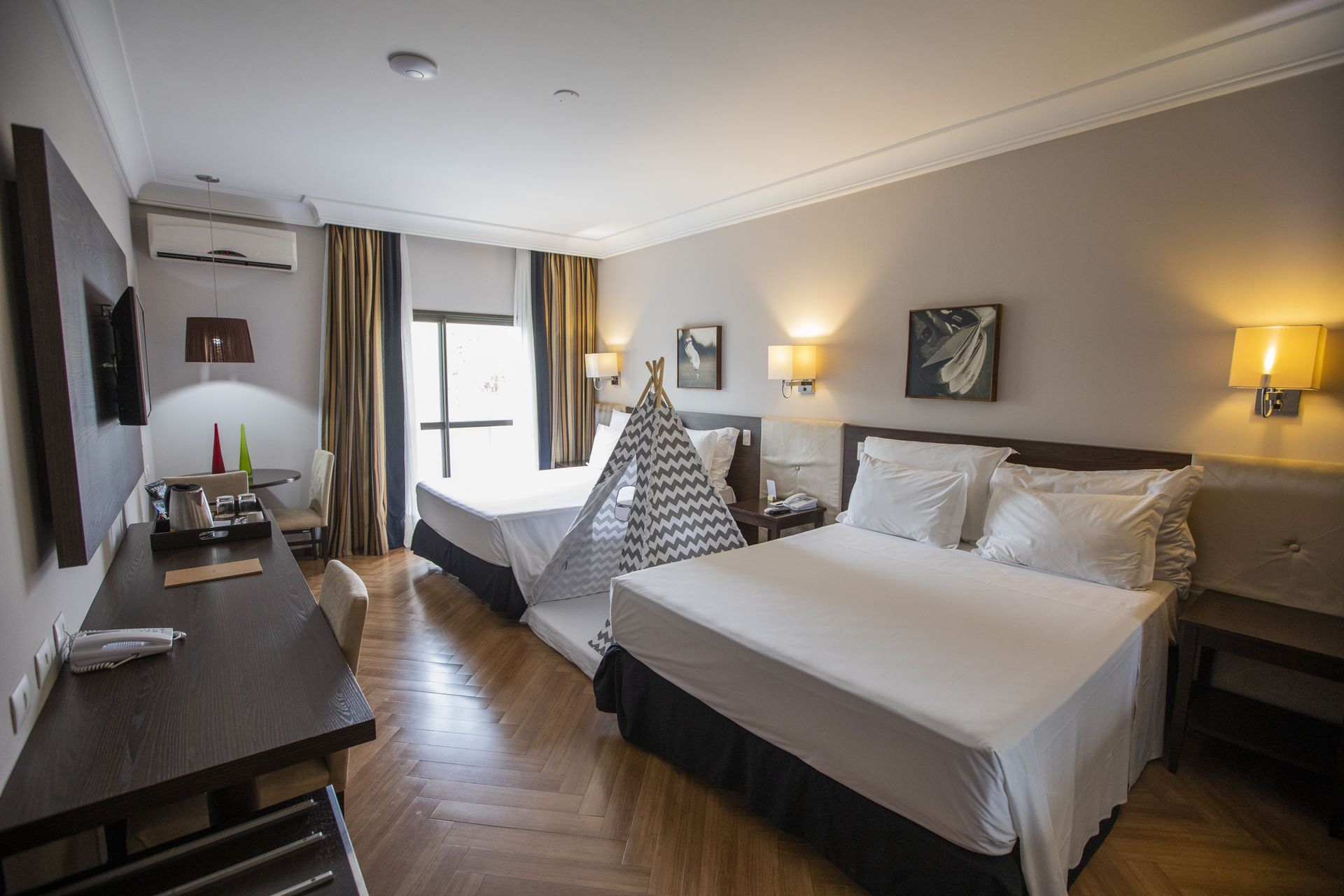 Um quarto de hotel com duas camas, uma escrivaninha e uma tenda.