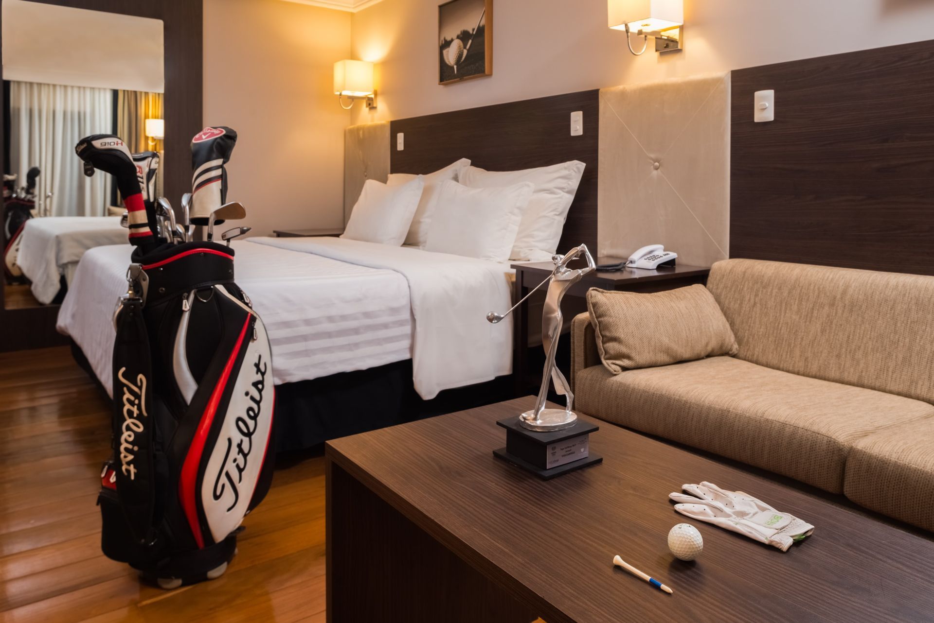 Uma bolsa de golfe está em um quarto de hotel ao lado de uma cama.