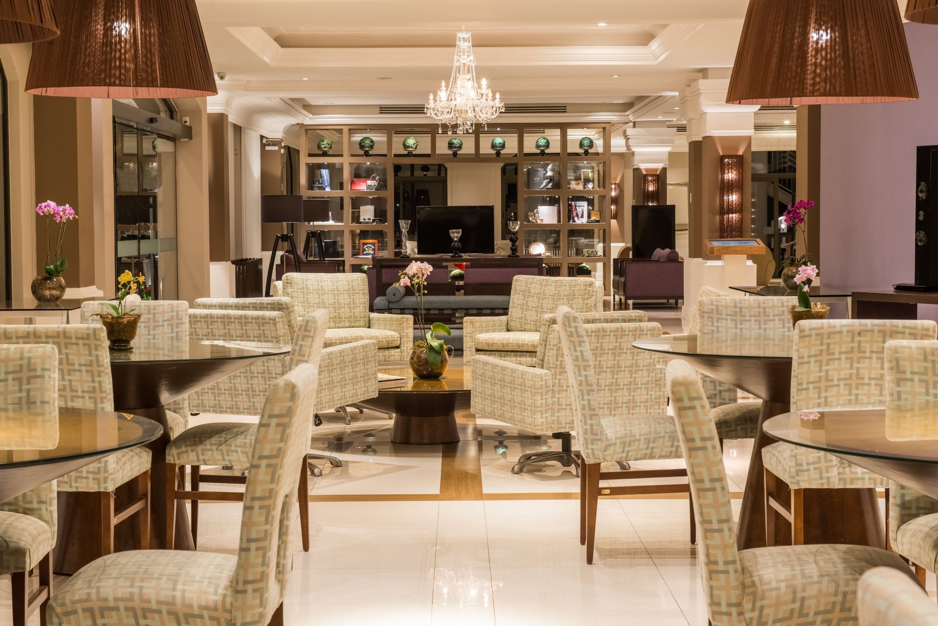 Um lobby de hotel com mesas, cadeiras e um lustre.