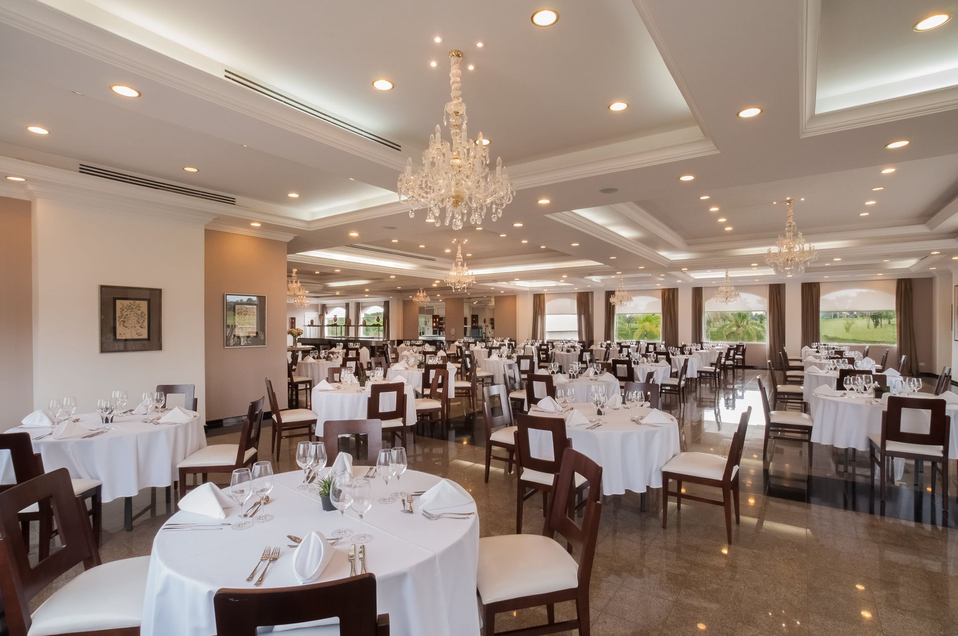 Uma grande sala de jantar com mesas e cadeiras e um lustre