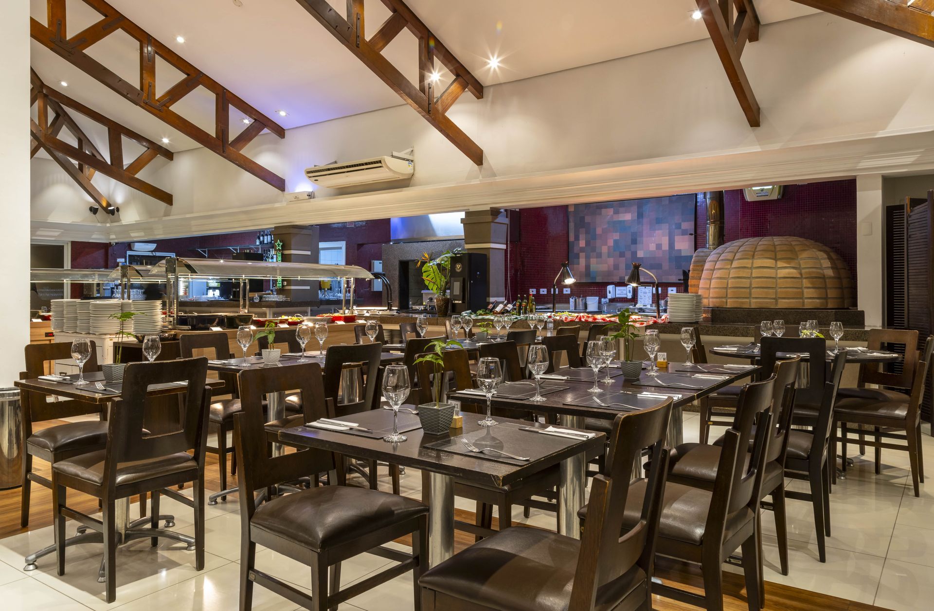 Um restaurante cheio de mesas e cadeiras e um forno de pizza.