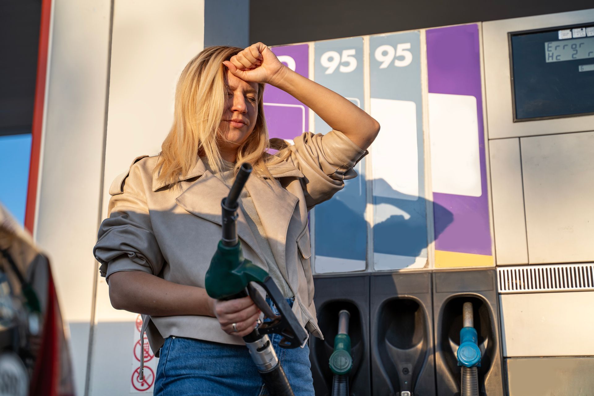 A person is holding a fuel nozzle at a petrol station.