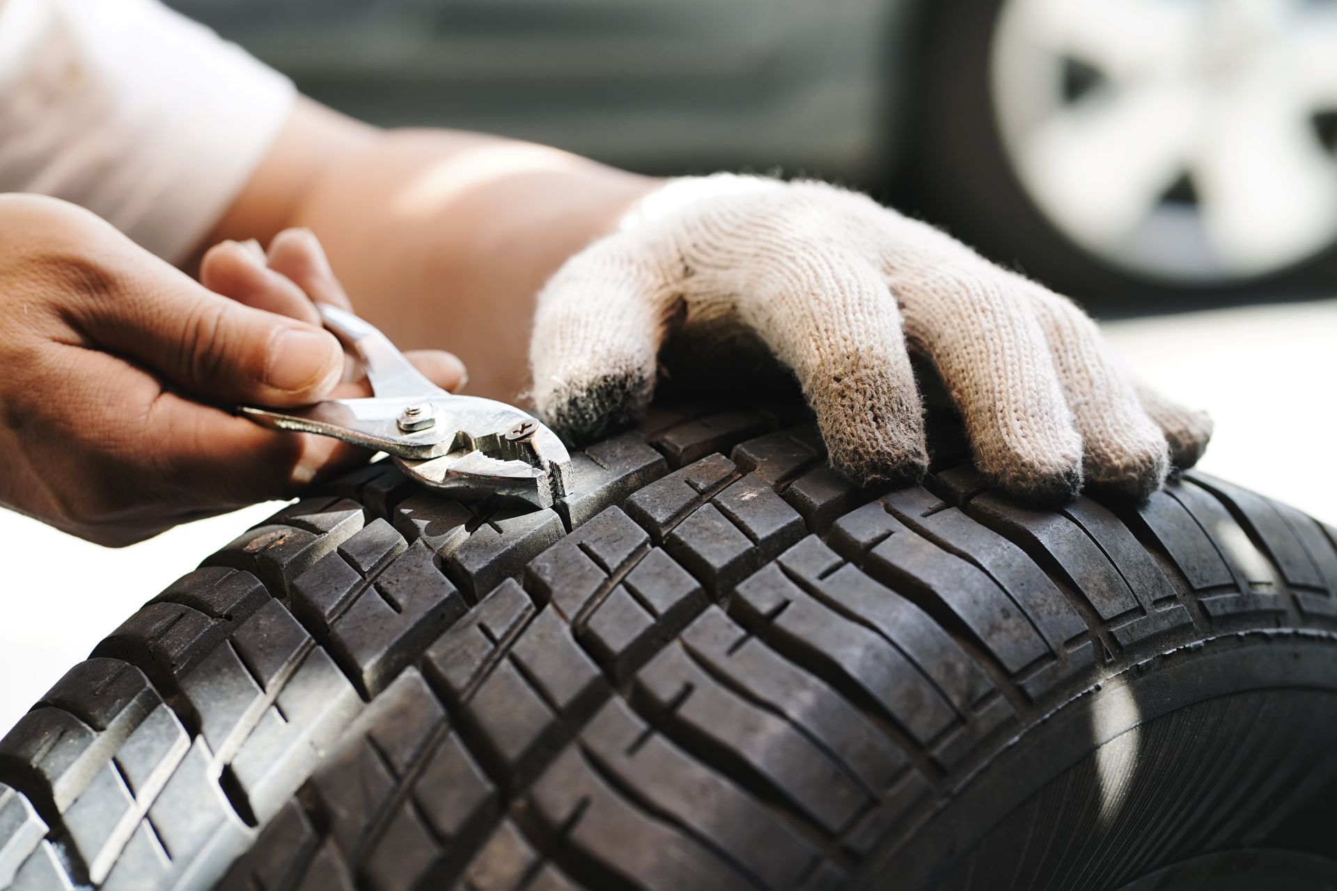 Close-up of a mechanic performing a tyre repair, removing a nail with a screw. Close-up of a mechanic performing a tyre repair, removing a nail with a screw.