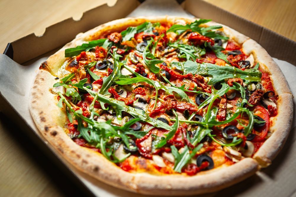A Pizza is Sitting in a Cardboard Box on a Wooden Table — Michelangelos Pizza & Pasta in Hermit Park, QLD