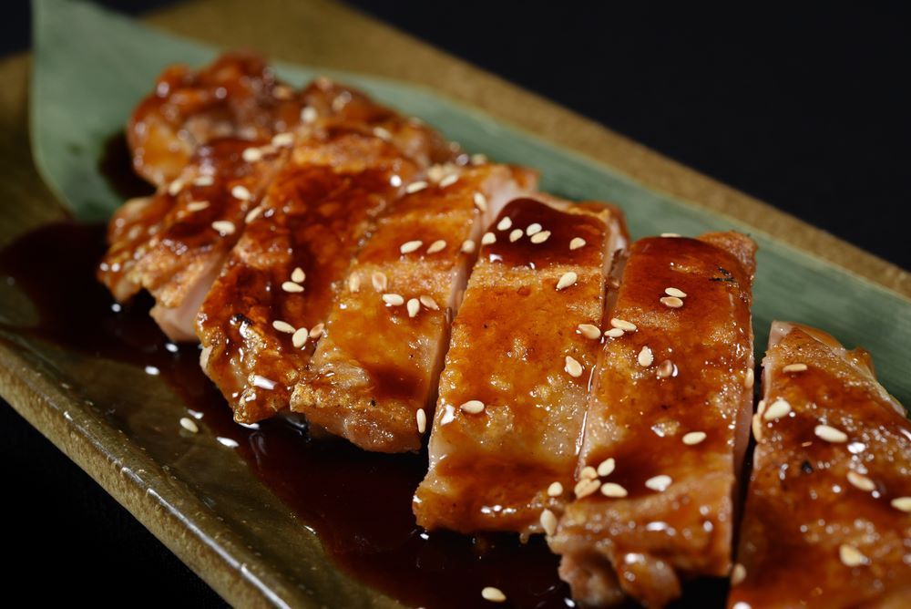 A Close Up of a Plate of Food With Sauce and Sesame Seeds on a Table  — Michelangelos Pizza & Pasta in  Kelso, NSW