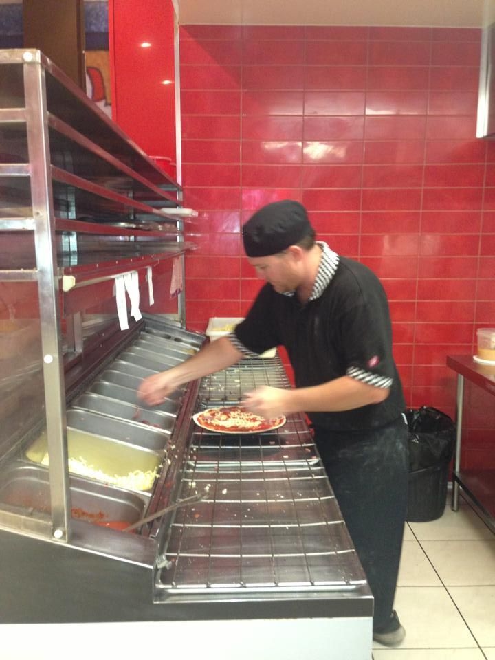 A Man is Preparing a Pizza in a Kitchen — Michelangelos Pizza & Pasta in Burdell, QLD