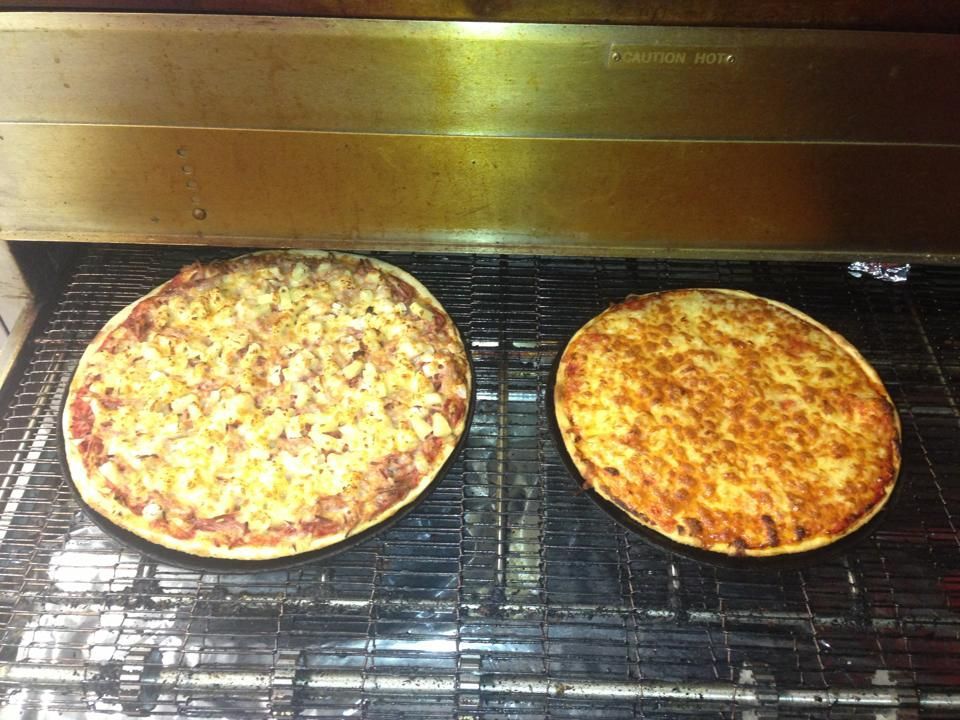 Two Pizzas Are Sitting on a Conveyor Belt in an Oven — Michelangelos Pizza & Pasta in Burdell, QLD