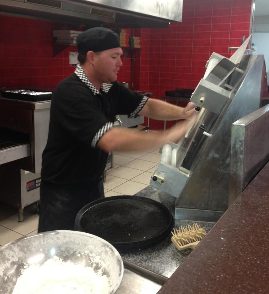 A Man in a Black Shirt is Working in a Kitchen — Michelangelos Pizza & Pasta in Aitkenvale, NSW