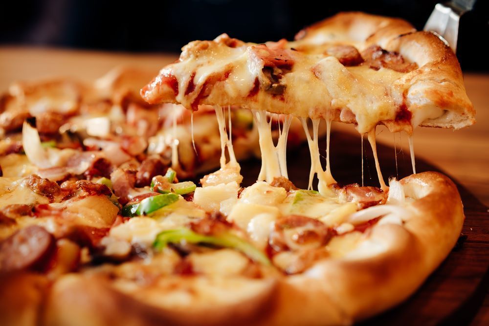 A Pizza With a Slice Being Taken Out of It — Michelangelos Pizza & Pasta in South Townsville, QLD